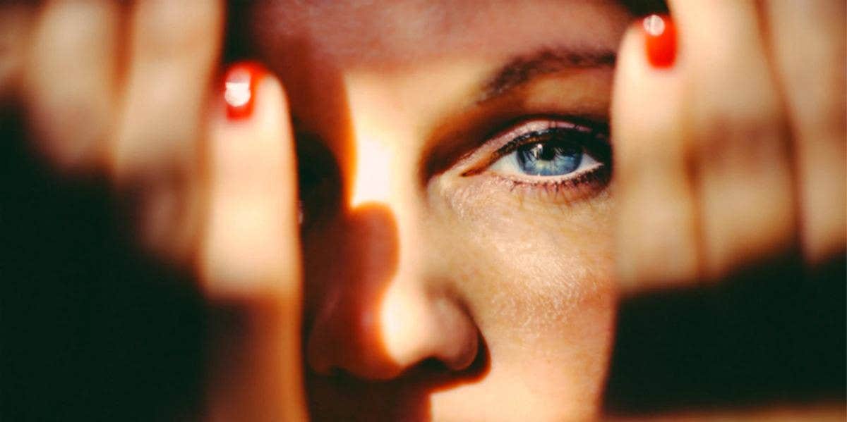 Woman with hands partially covering face to hide