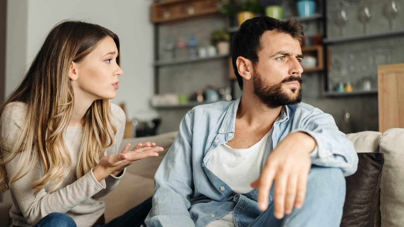 woman pleading with boyfriend during argument while the two sit on a couch at home
