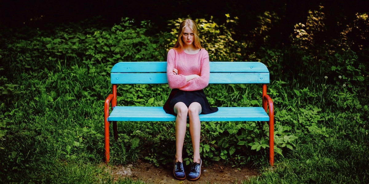angry woman sitting on a bench with arms crossed