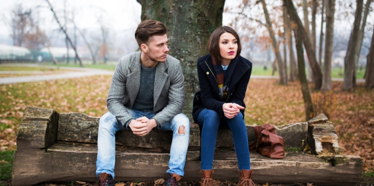 woman and man sitting on a bench angry at each other