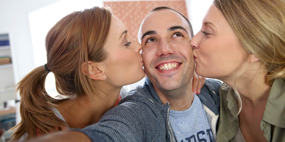 How To Tell If You're Polyamorous — Or Just Afraid Of Commitment two women kissing cheek of man