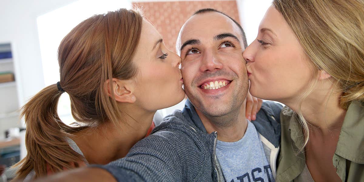 two women kissing cheek of man