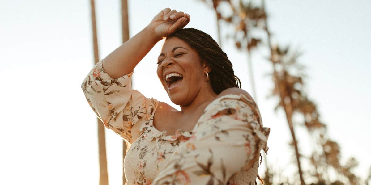 Influencer Arielle Estoria laughs in front of a line of palm trees