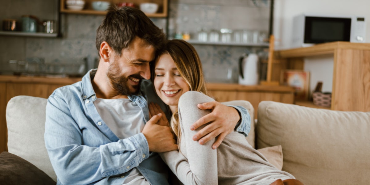 man and woman cuddling on couch in love