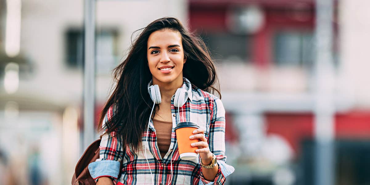 It's hard for ADHD people to ask for help Young Latina woman crossing a city street with coffee and headphones