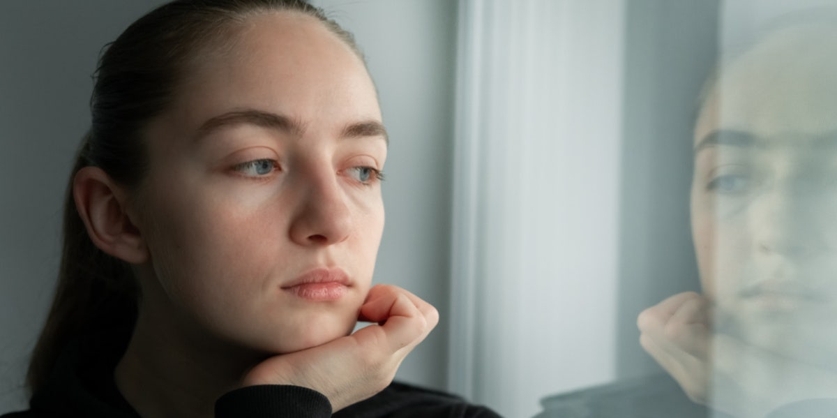 sad woman looking out the window reflection