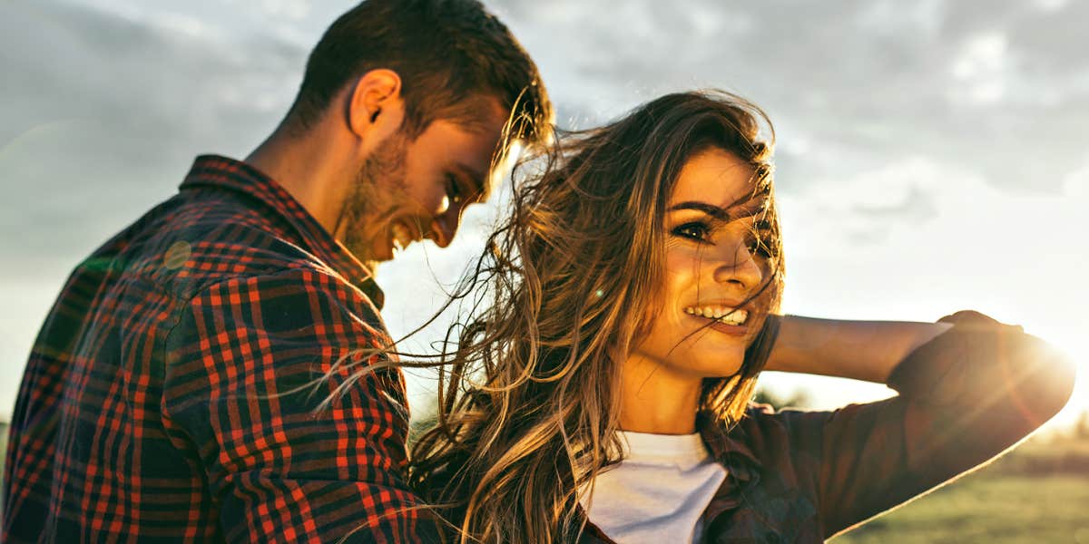 man and woman in a field, sunset behind them