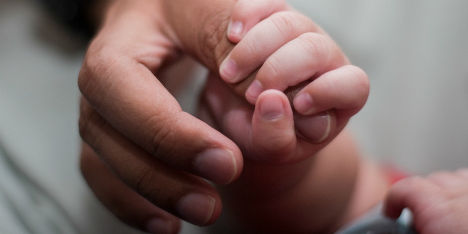 Meet The Blue-Eyed Man Sired 22 Kids (And Counting!) With Donated Sperm adult hand clutching a baby hand