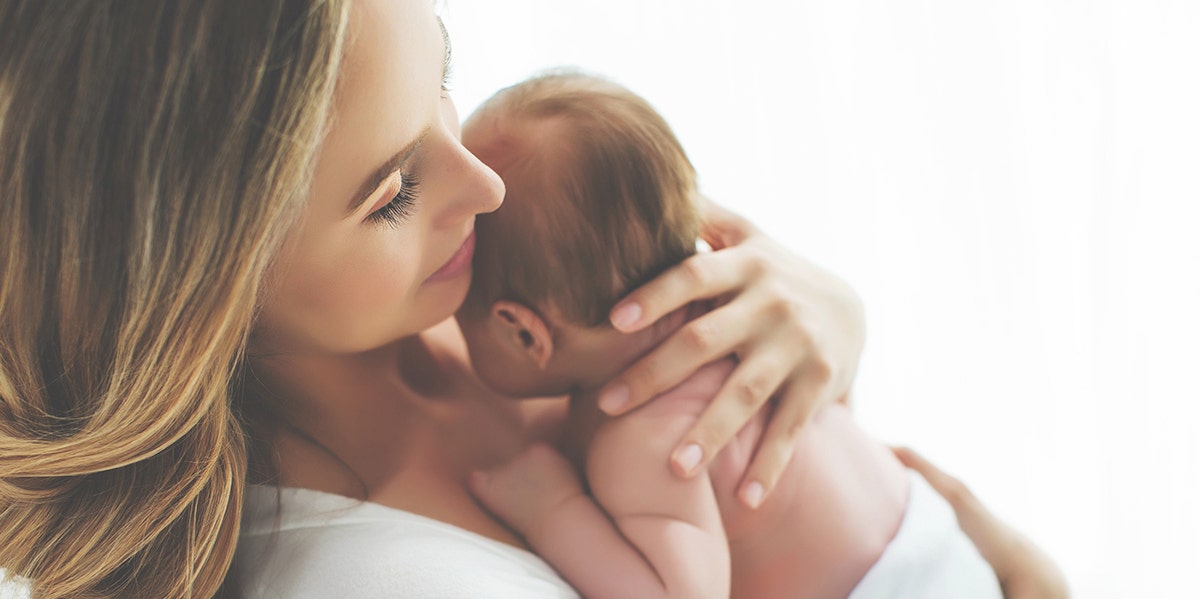 Woman holds a small newborn close to her chest