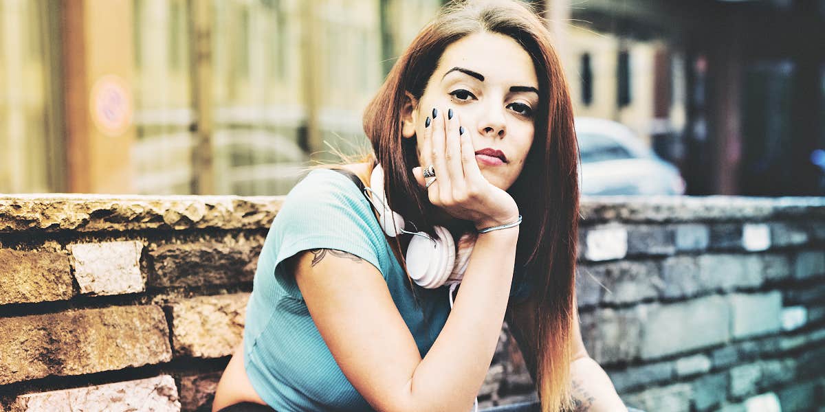 woman with long brown hair looks at camera with eyebrow raised