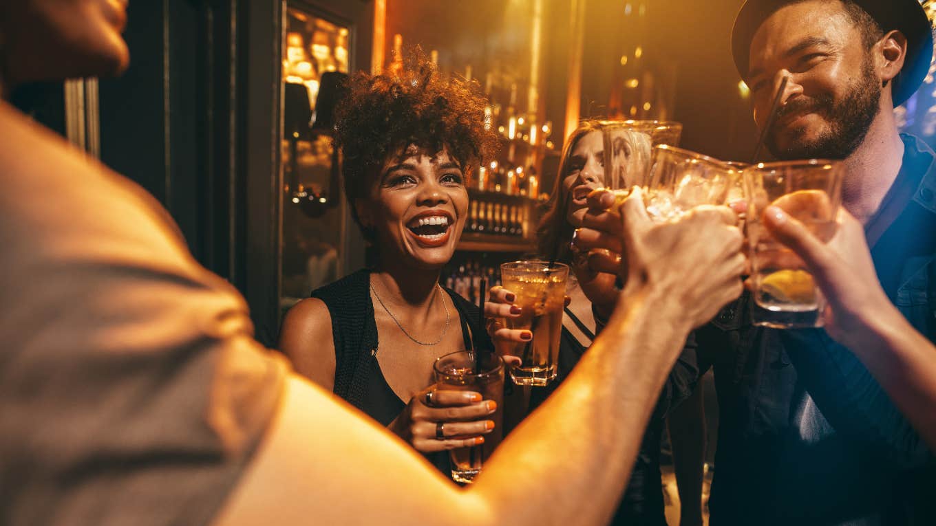 Group of young people toasting drinks at nightclub.