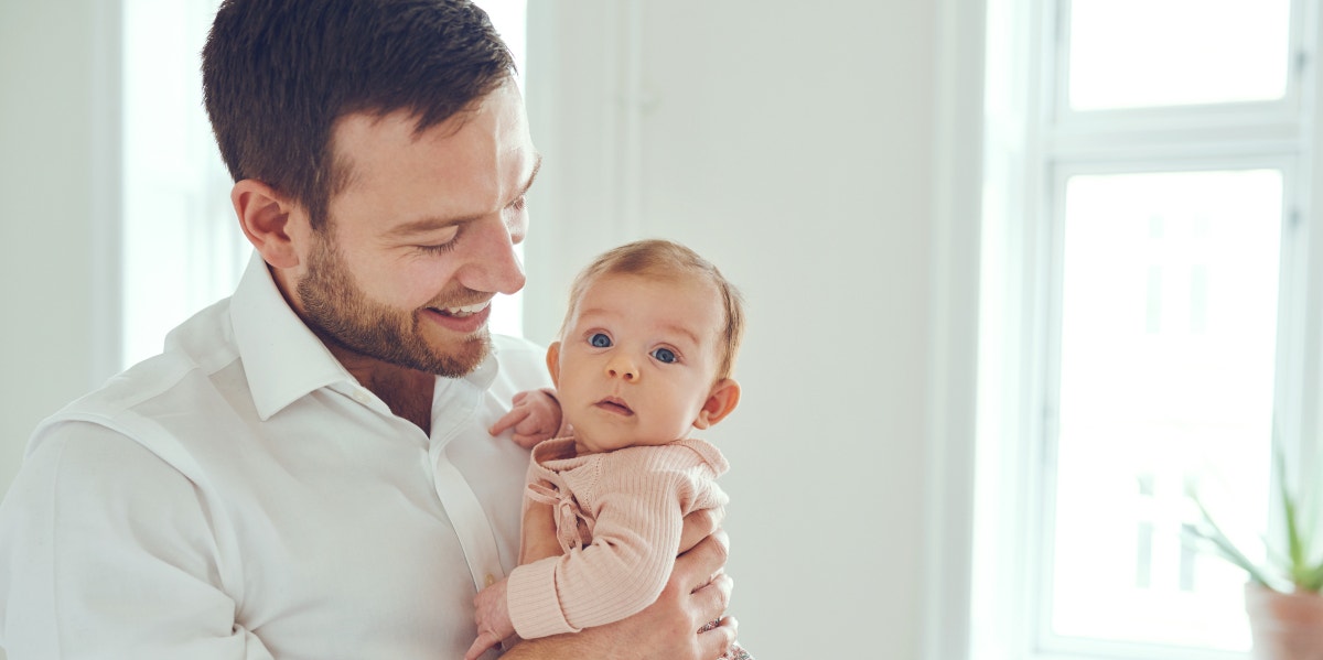 man holding baby and smiling