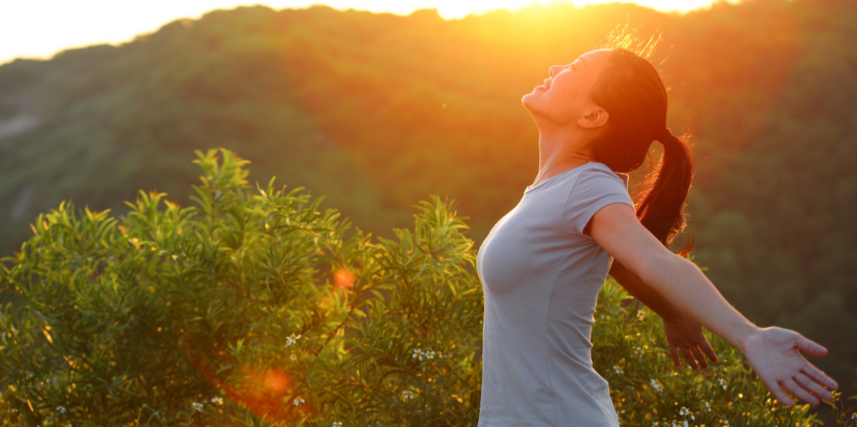 woman holding out arms in sunshine