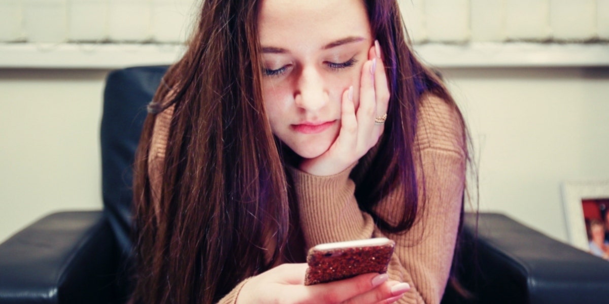 woman looking down at cell phone