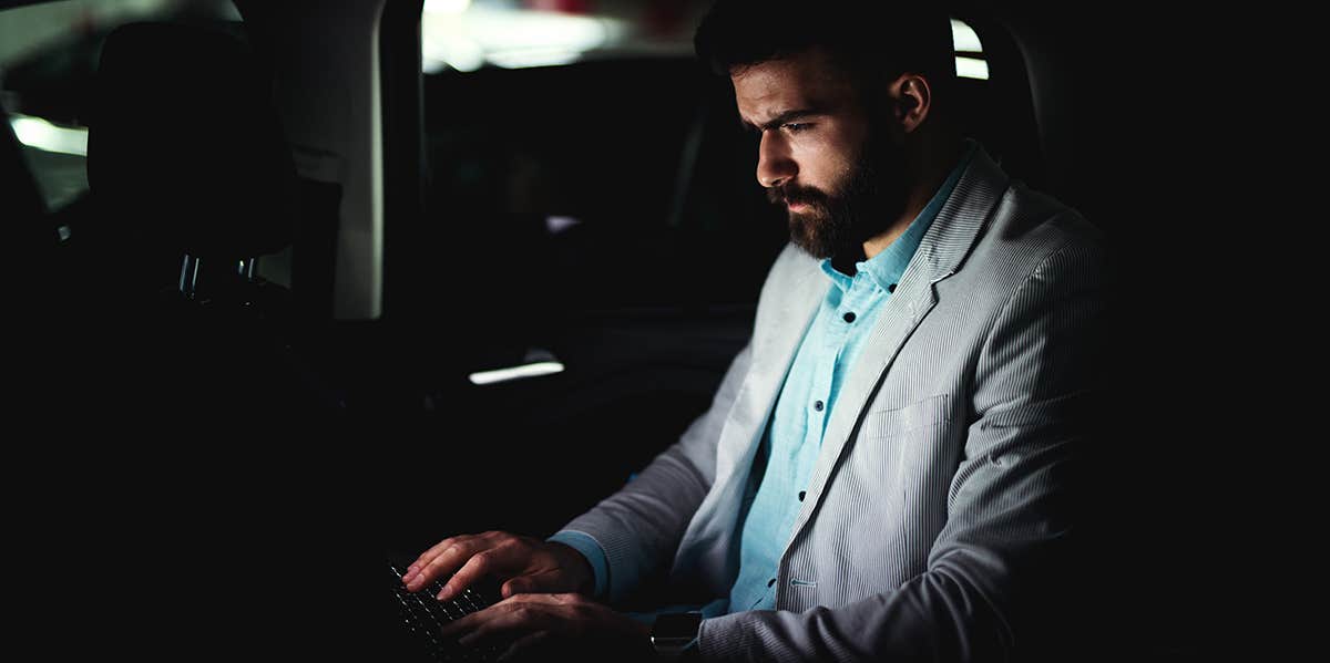 7 Sneaky Benefits of Hustling That Have Nothing to Do with Money, Success Or Power guy typing on laptop doing work at night in back of car