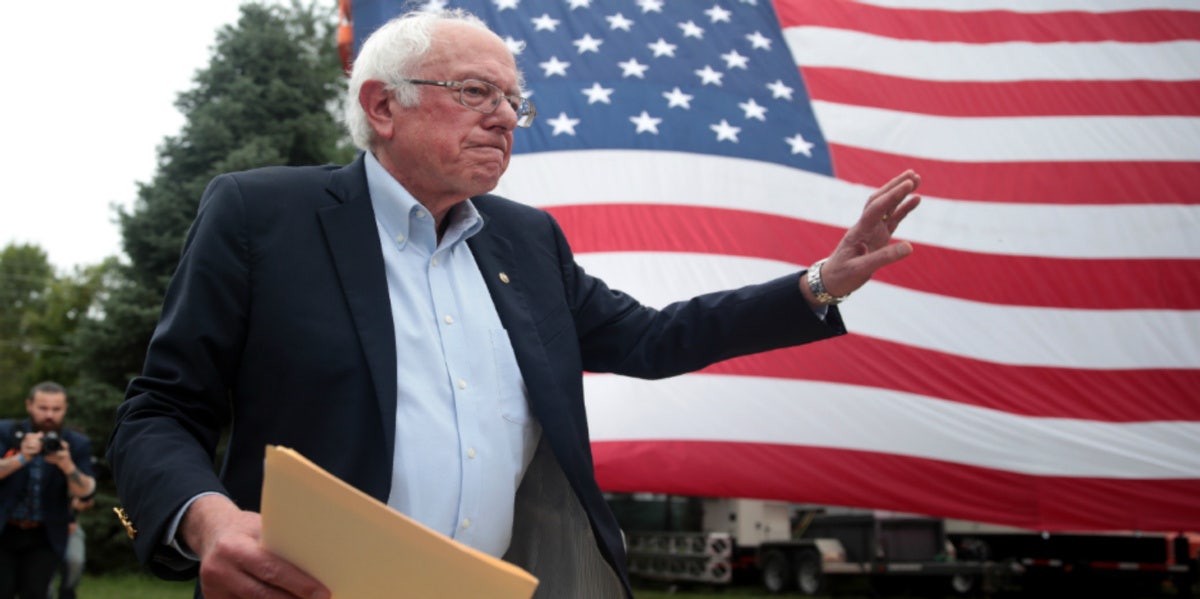 bernie sanders holding envelope in front of american flag