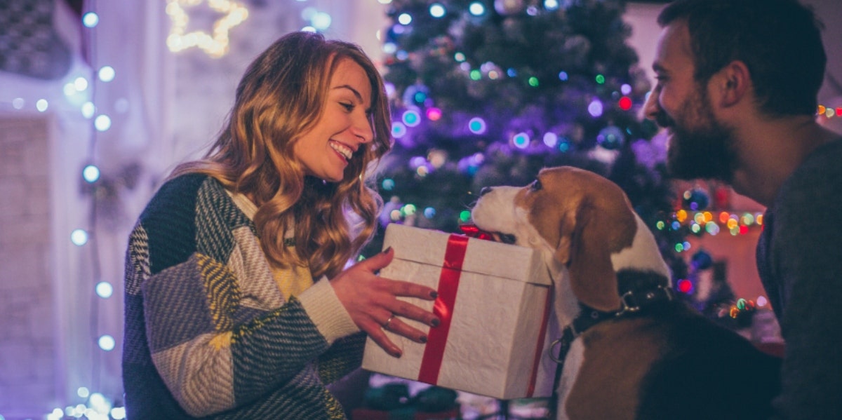 Best Beauty Products To Give As Stocking Stuffers (2020) husband and dog giving wife christmas gift