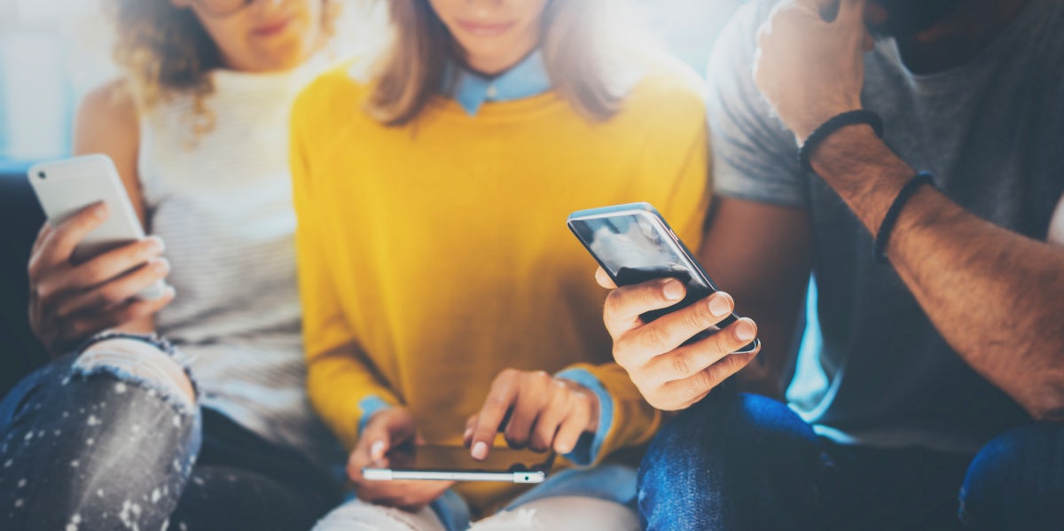 three young adults looking at dating apps on their phones 