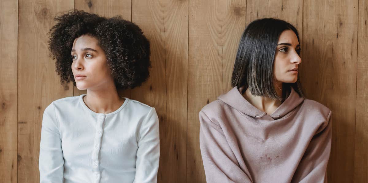 pensive women near wooden wall looking away from each other