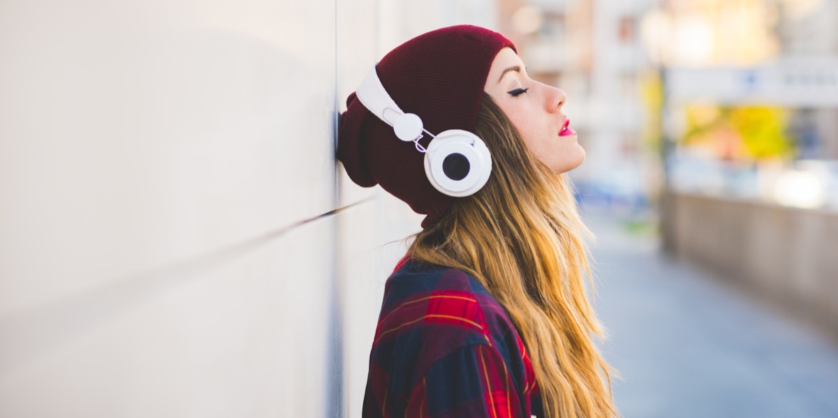 woman with headphones against wall