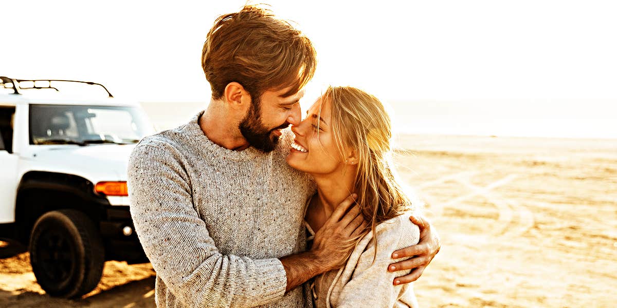 Couple nuzzling lovingly in desert in front of a Toyota SUV