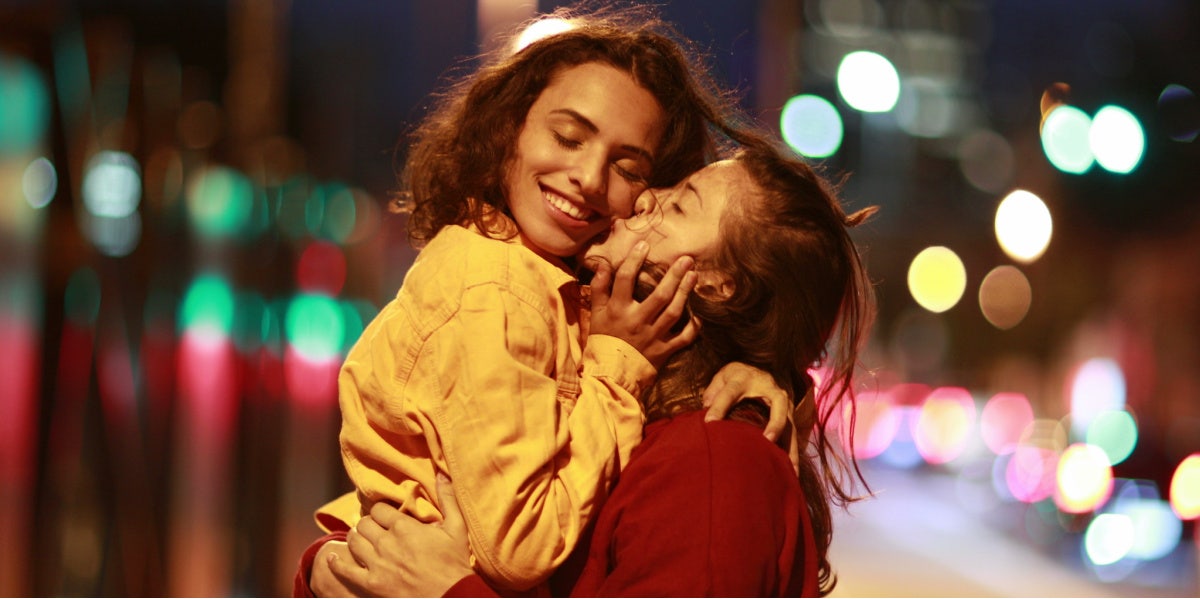 woman kissing another woman on the cheek city streets