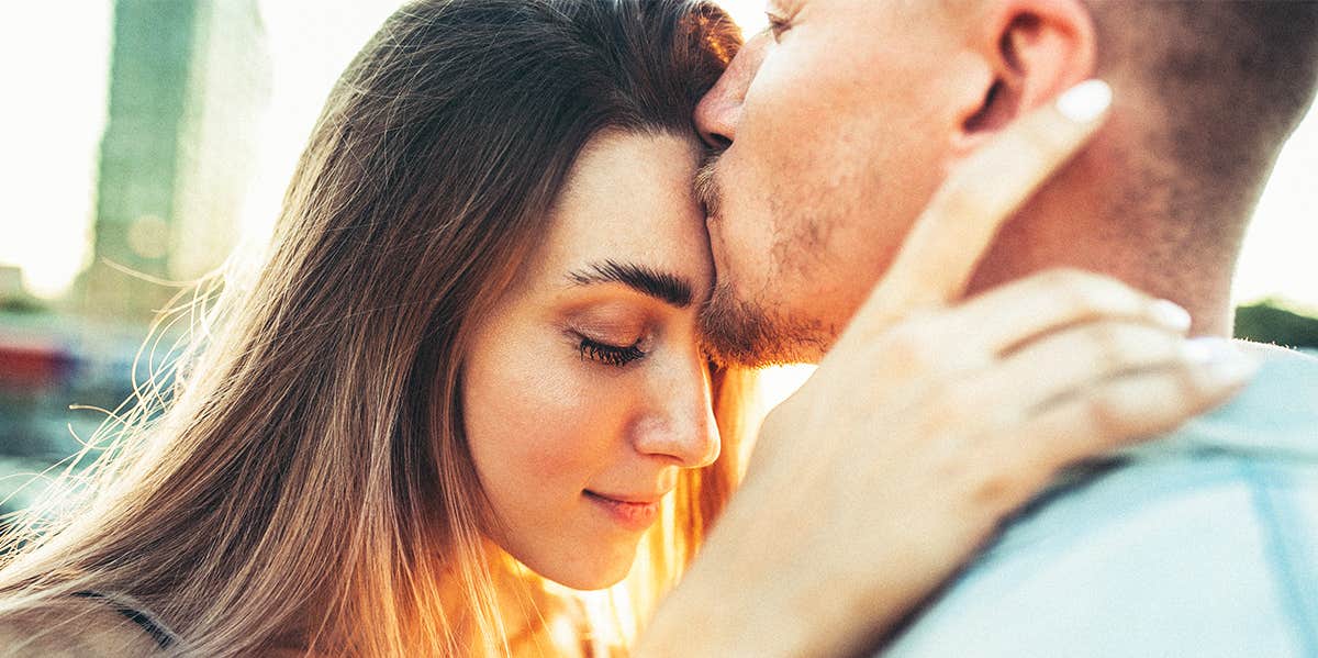 man kissing woman on forehead