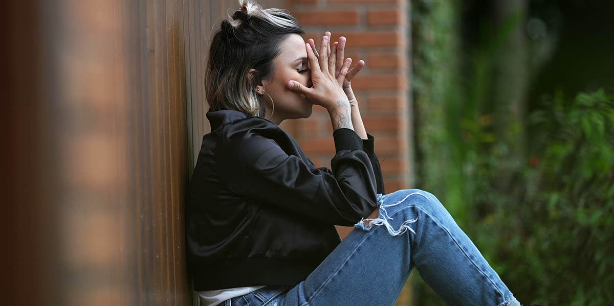 upset woman sitting against fence