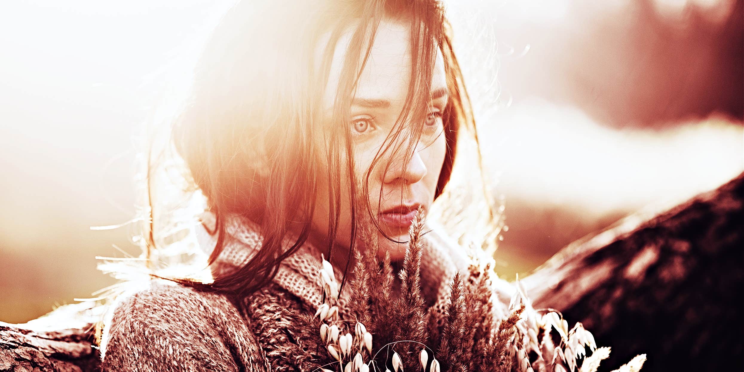 Biochemical ways your brain tricks us into loving abusers woman looking sad holding flowers, sun behind her head