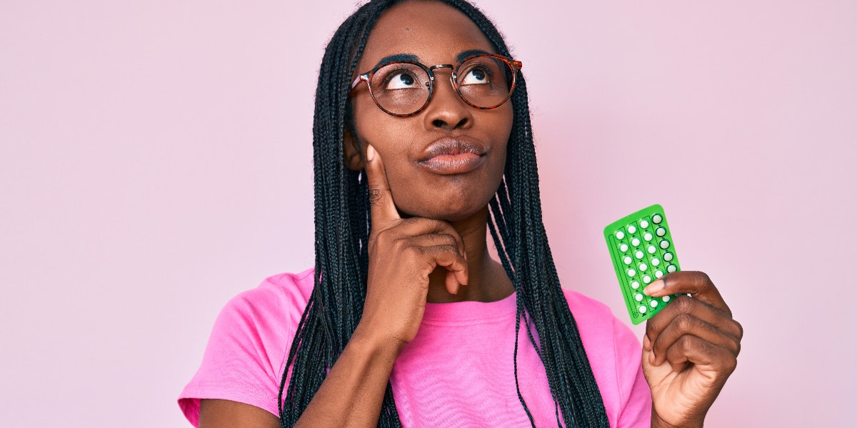 contemplative woman holding birth control pills