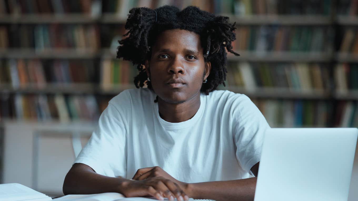 black student with dreads studying at table with laptop