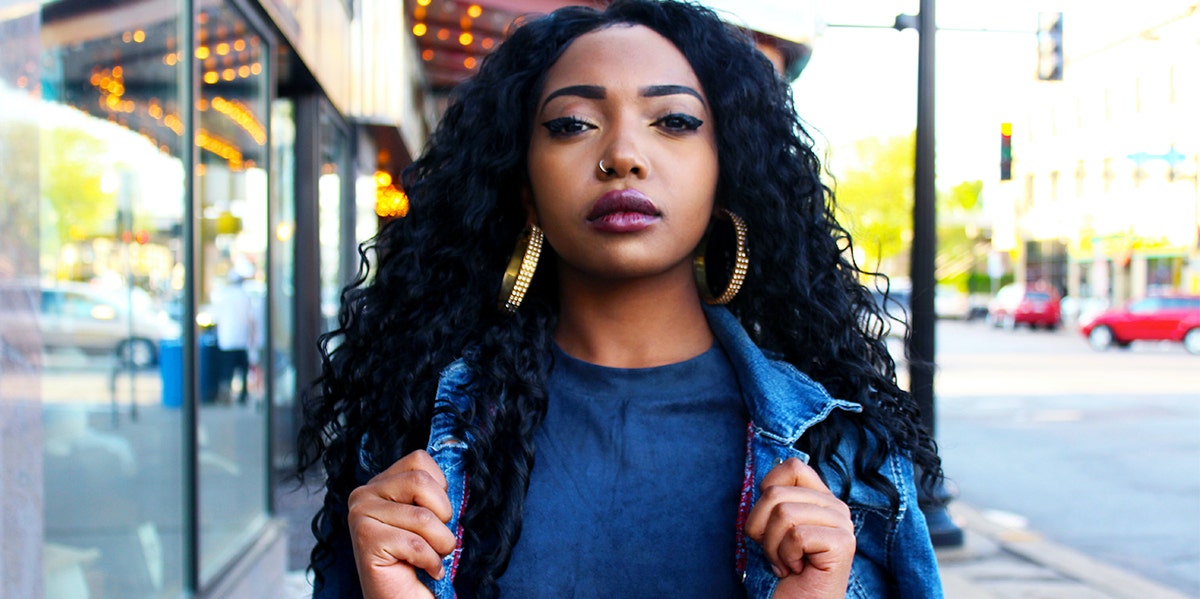 Black woman posing on the sidewalk in denim jacket