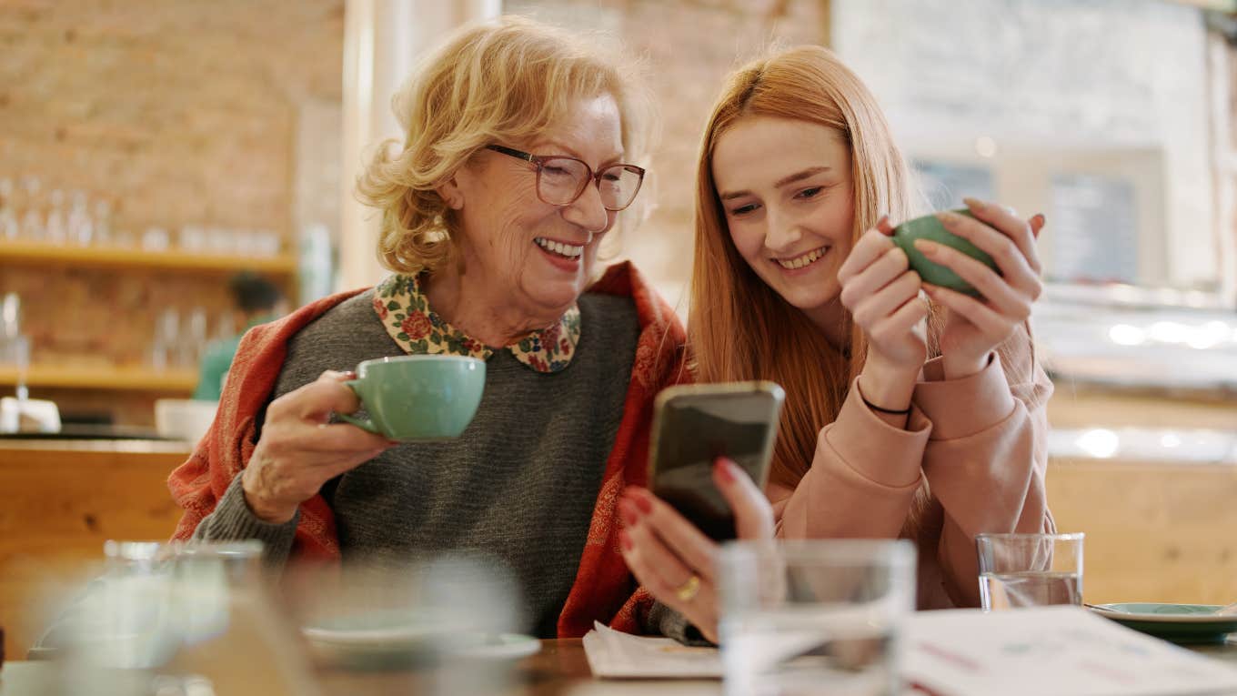 Older woman laughing and hugging a young girl. 