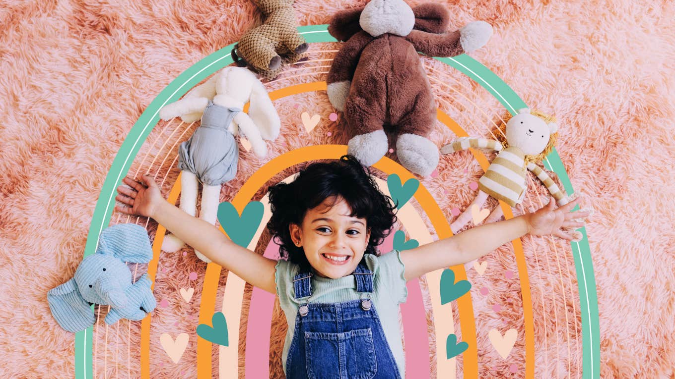 girl smiling laying on ground with stuffed animals