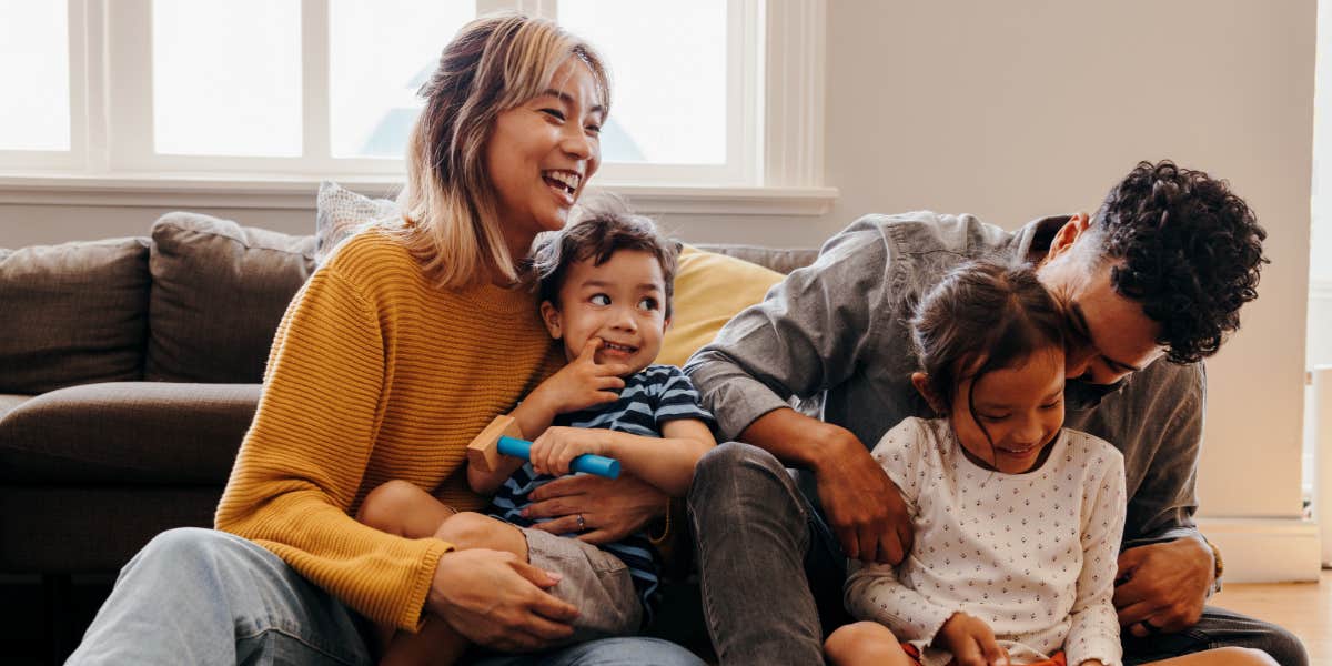 Young family of mixed race cuddles children in the living room