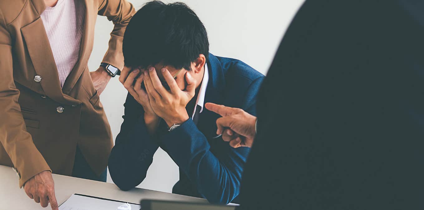 bosses firing sad employee with his head in hands