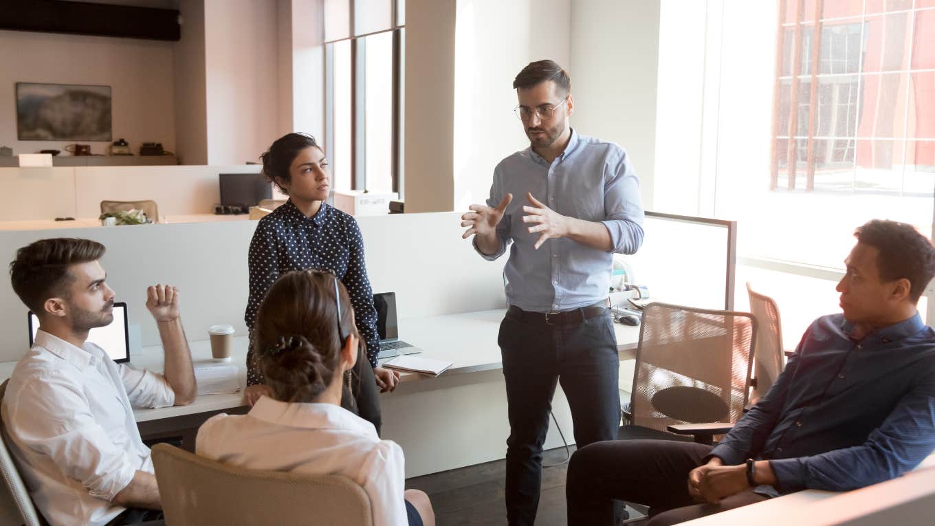 boss talking to group of employees in office