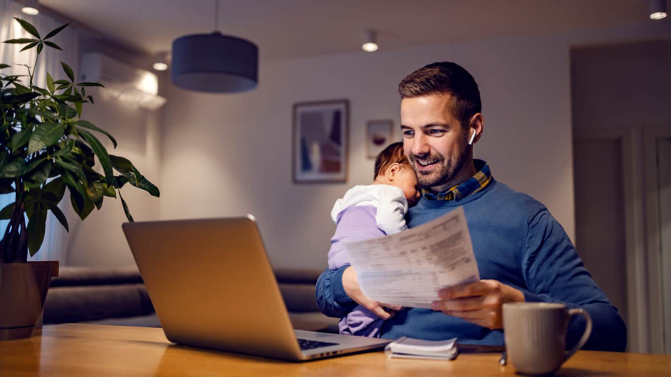 young dad works from home holds his sleepy baby girl in his hands