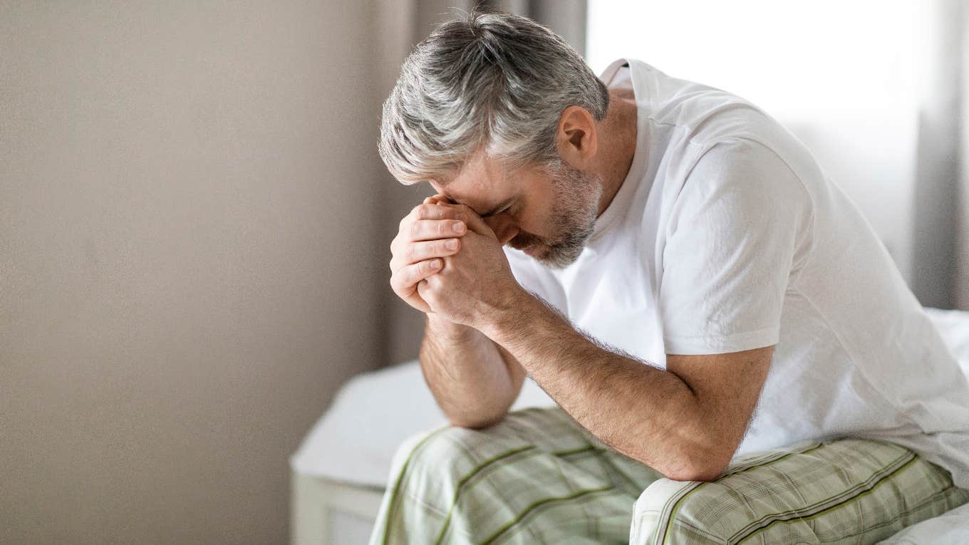 man in pajamas with head in his hands