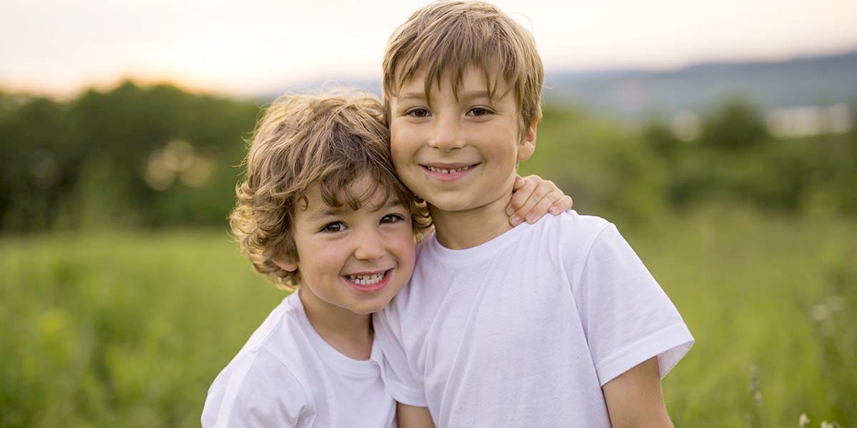 two kids standing together in field