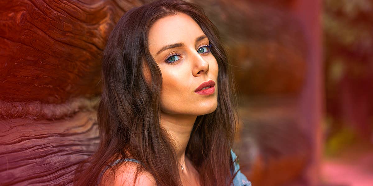 single woman posing near wooden building