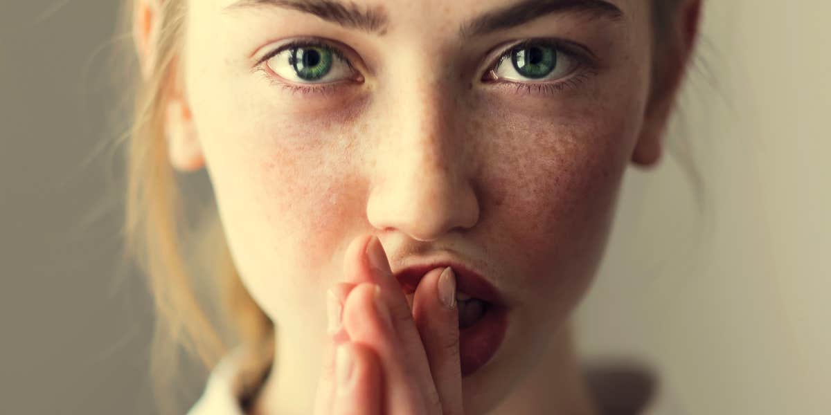 young blonde woman with green eyes stares intensely at camera