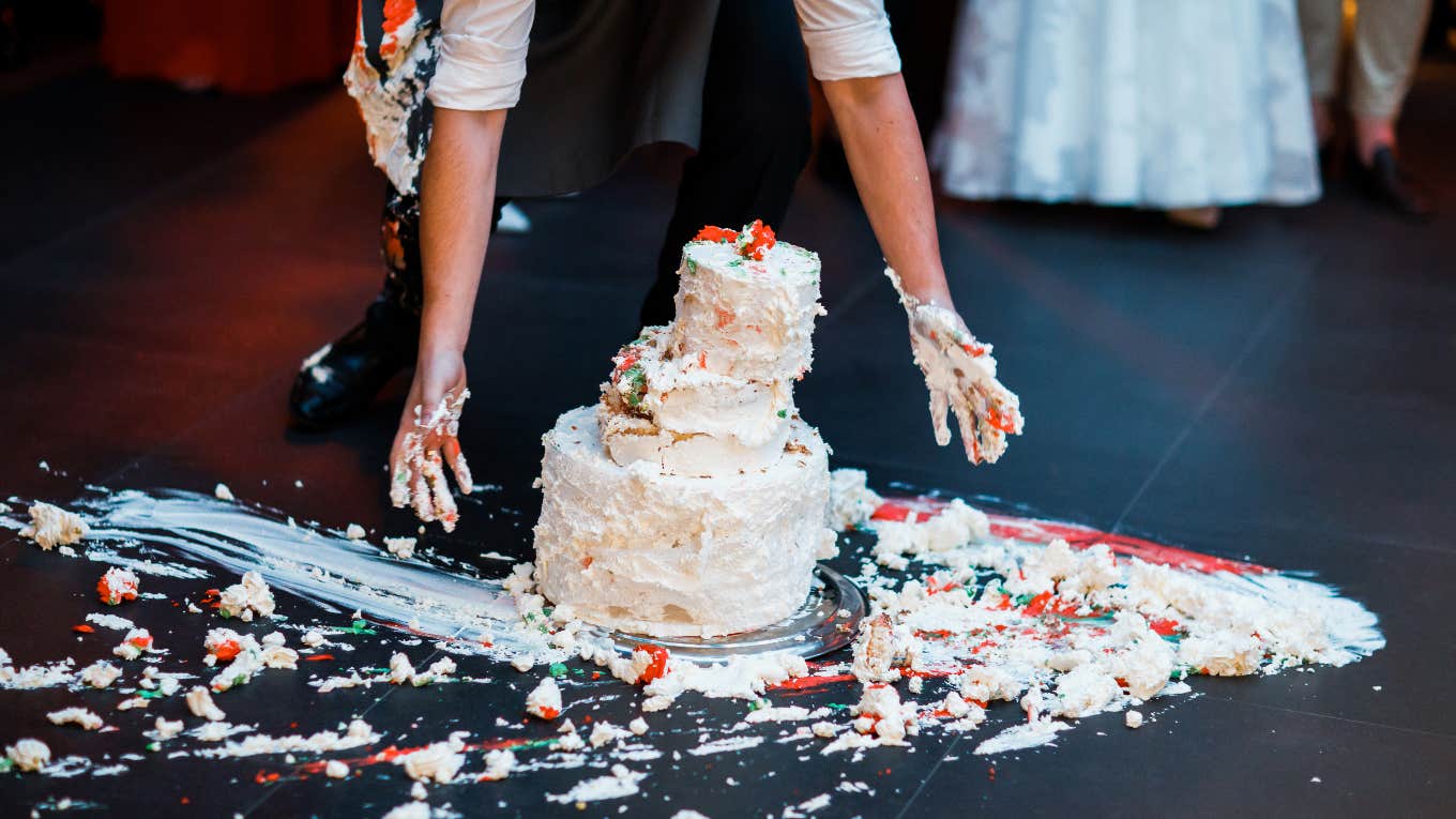 person picking up smashed wedding cake from the floor