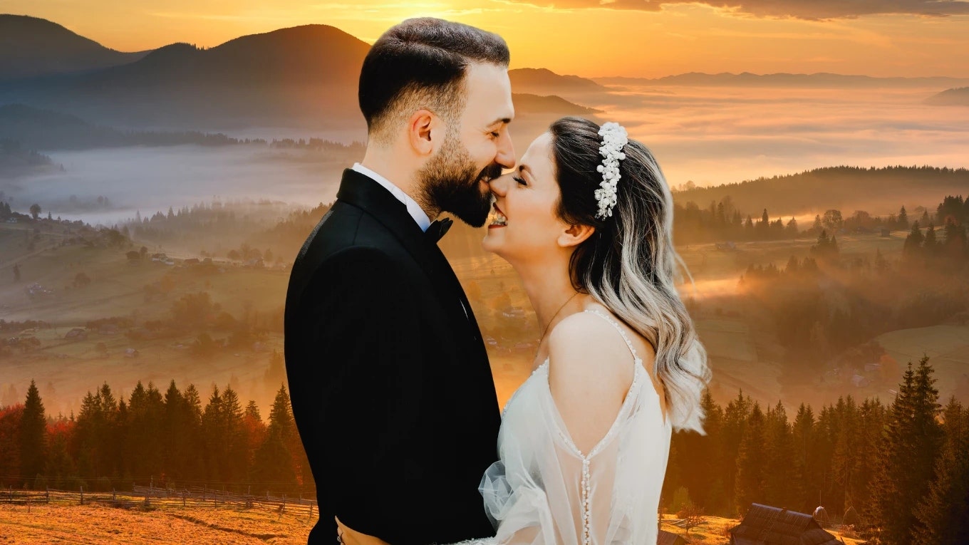 Bride and groom kiss in front of a sunrise at their wedding