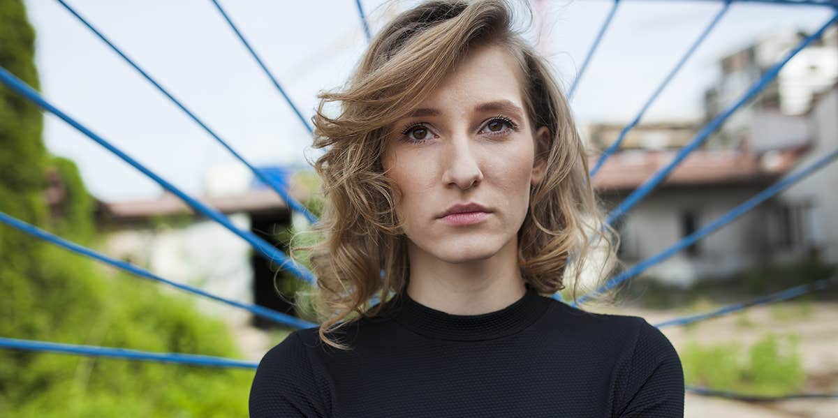 woman with wavy hair and solemn face looking direct at camera