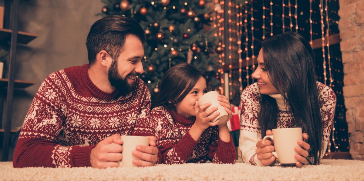 parents and daughter drinking hot cocoa at christmas
