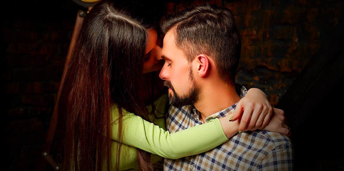 woman kissing man sitting on his lap