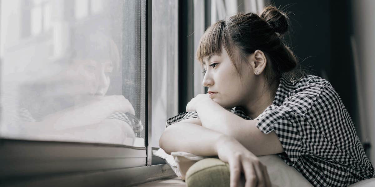 lonely woman looking out a window