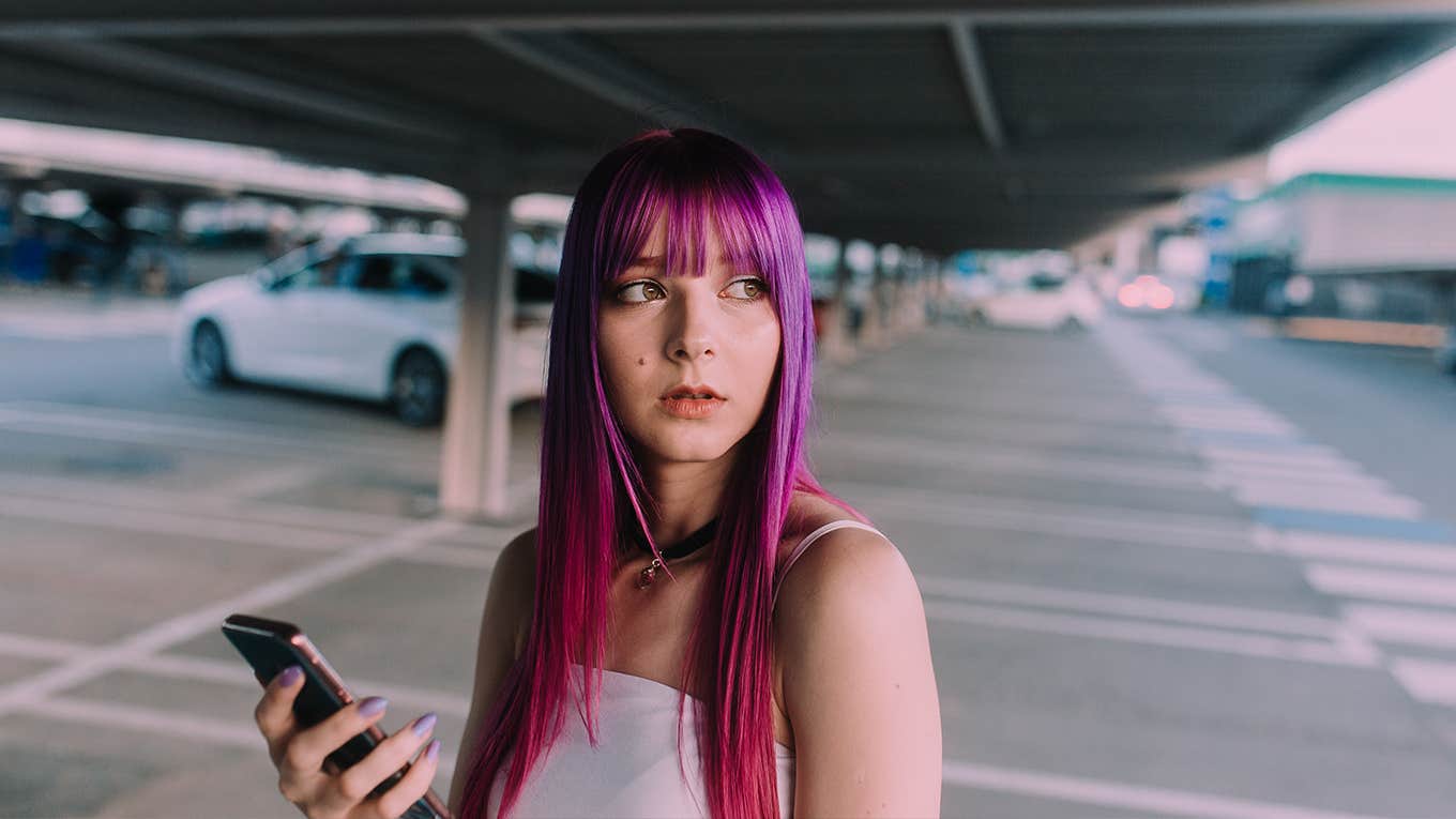 woman with purple hair doing a phone call standing with an urban background