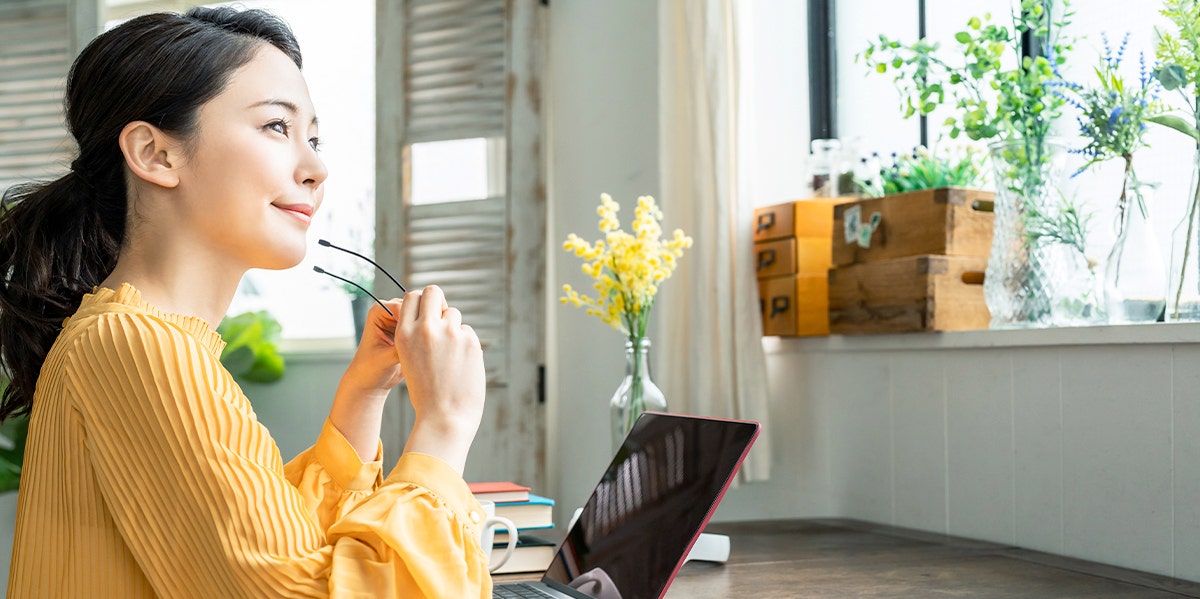 woman putting on glasses in front of laptop